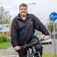 Man cycling on shared-use path, by Fife College Campus