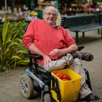 A man using a wheelchair and smiling on a residential street in Bristol 