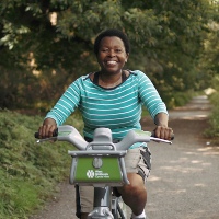 Algar, a Walking and Cycling Index survey respondent, smiling as she rides through a tree-lined path in Sutton Coldfield