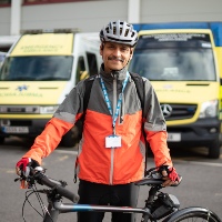 Sanjay, a  Consultant Pathologist at Southampton Hospital, smiles with his bike outside his place of work