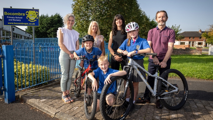 Children and staff from Bocombra Primary School join representatives from Sustrans and the funders PHA and DfI outside the school on a sunny day.