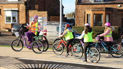 A woman leading a group of schoolchildren on bikes