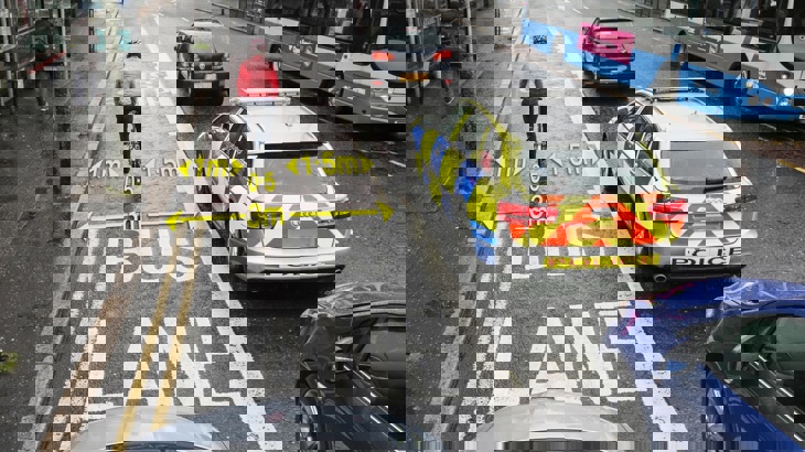 Cars and cyclist riding along ideal bike lane width with annotation
