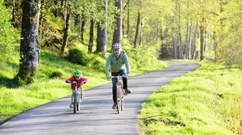 Man and child cycling on a greenway path
