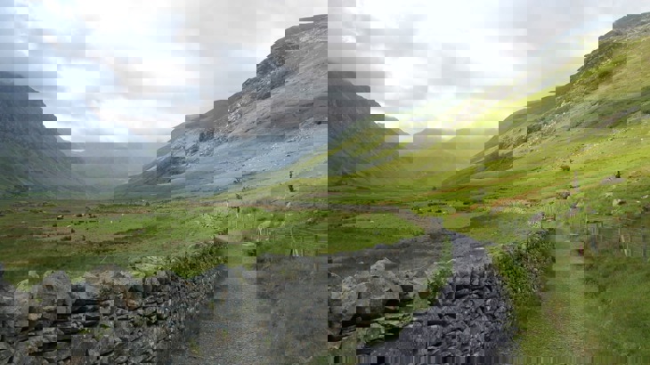 Grey stone wall and gravel track through Welsh valley with mountains
