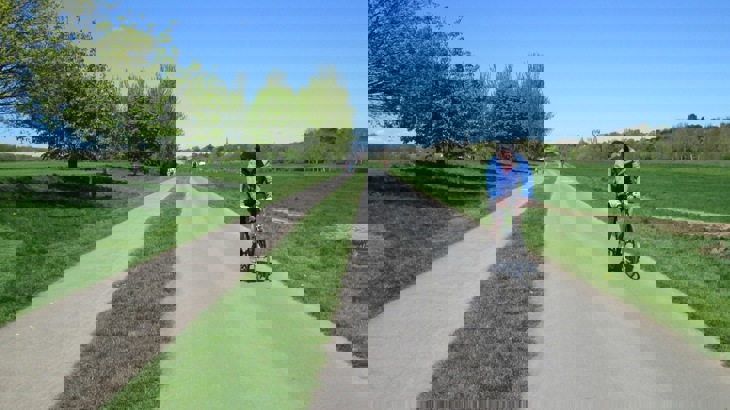 A person cycles along a traffic-free path surrounded by grass
