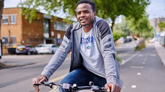 Man smiles as he cycles along a quiet segregated cycle lane in the city.